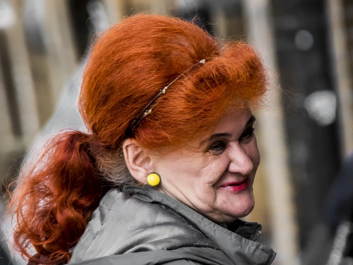 Woman with bright red hair smiling outdoors